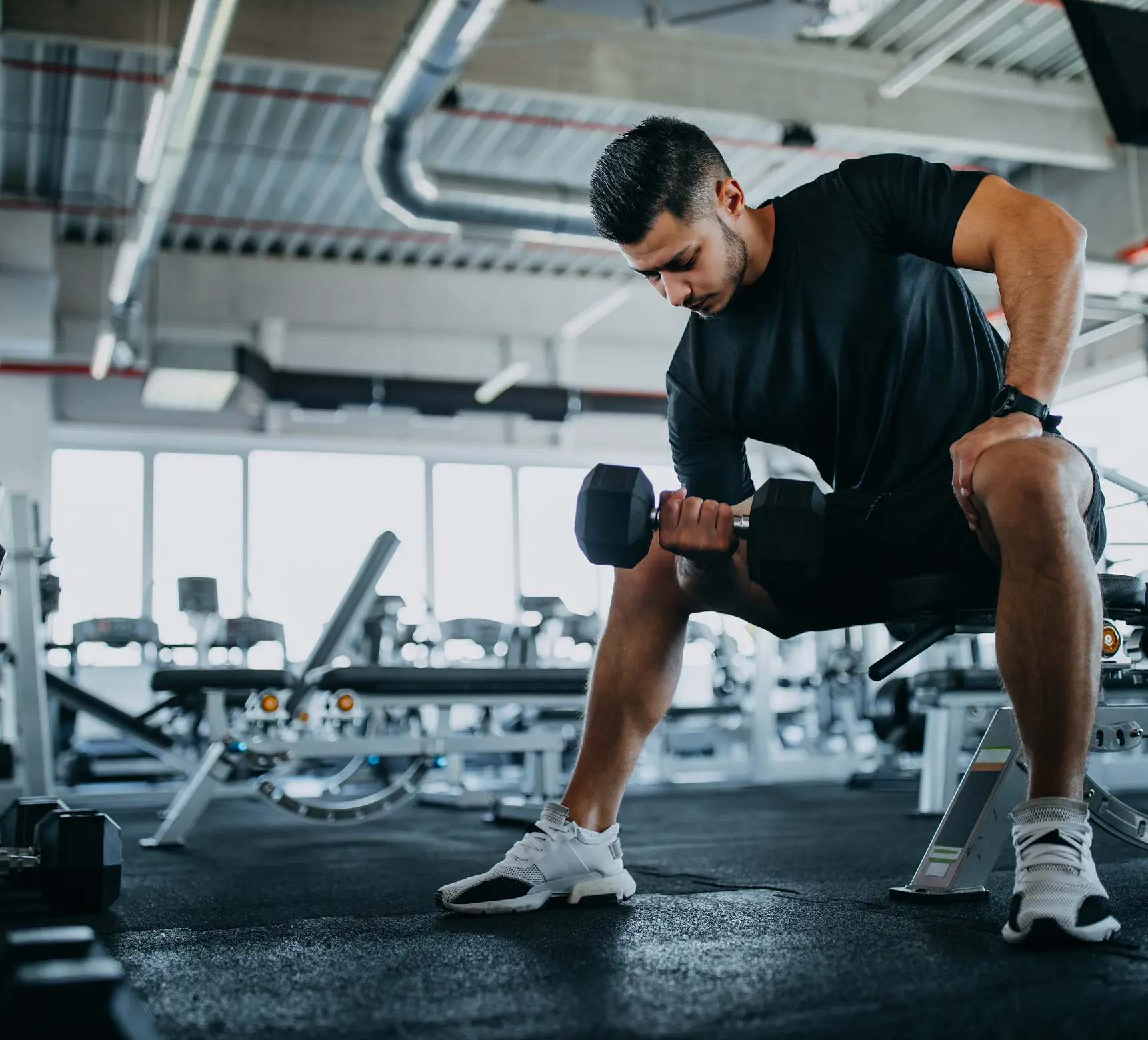 Man lifting dumbbell in gym setting.