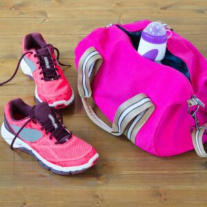 Pink gym bag and running shoes on floor.